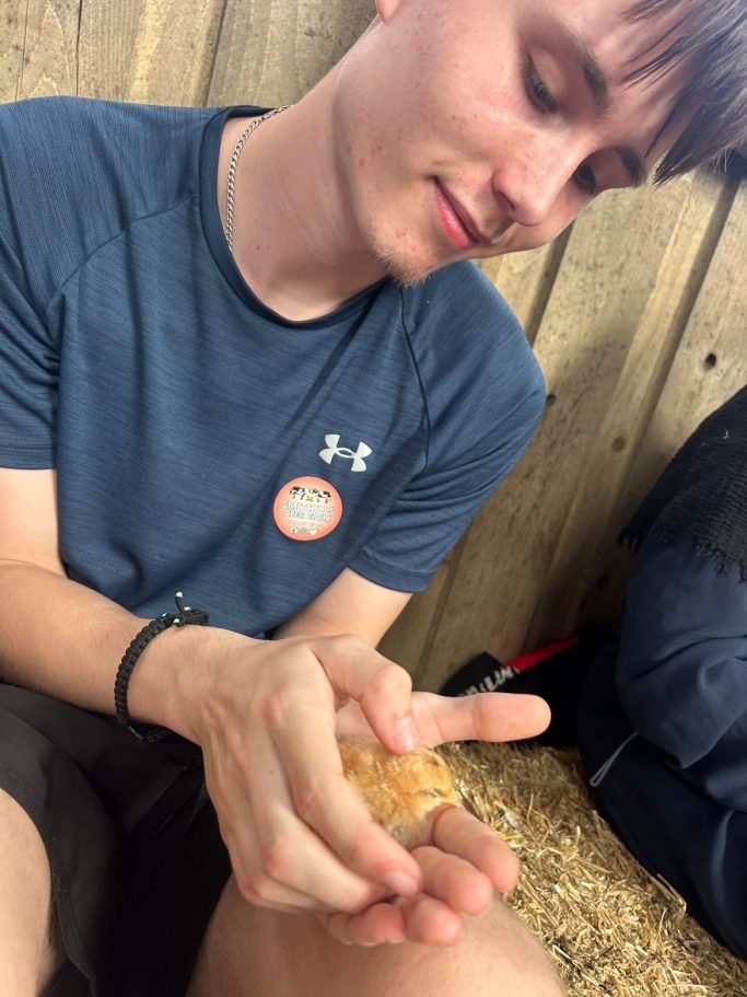 Young man holding a small animal in his hands, smiling.